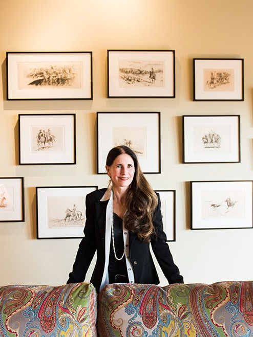 Woman standing in front of framed artwork above a colorful patterned sofa