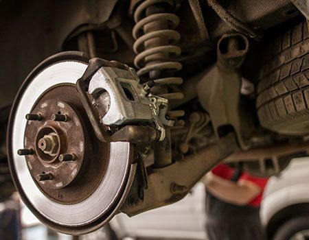 Close-up of a car brake rotor and caliper during repair under the wheel well