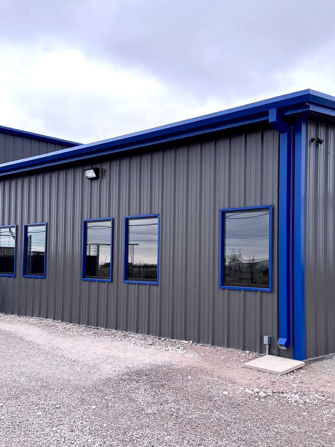 A gray metal building with blue windows and a blue roof.