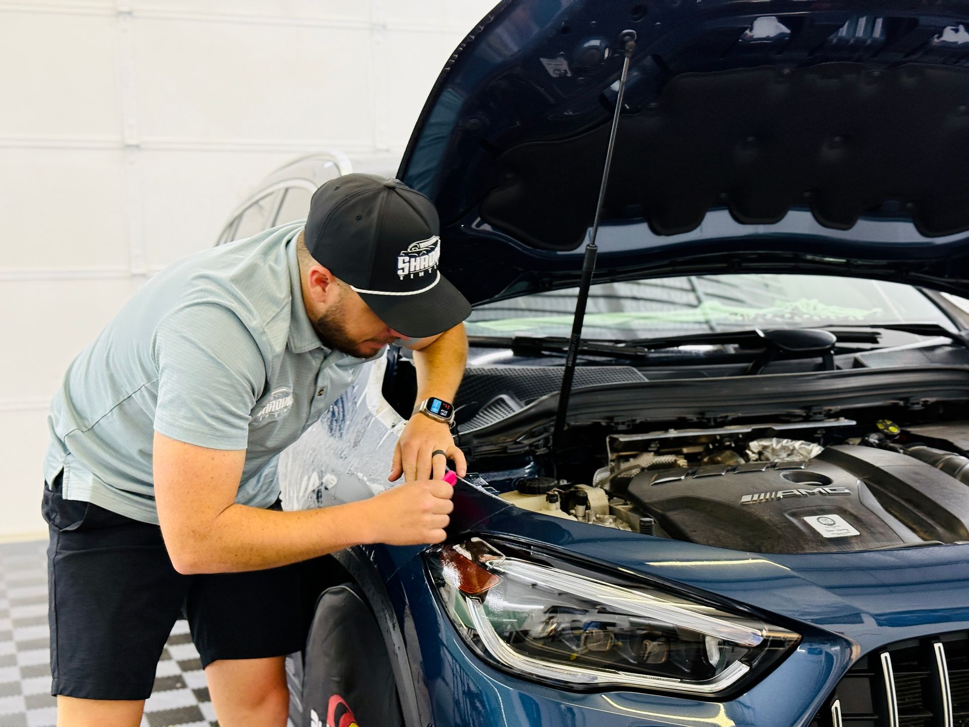 A man is working on the hood of a car.
