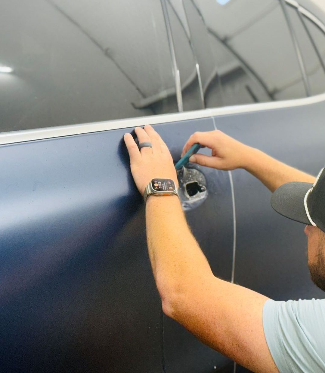 A man wearing a watch is working on a car