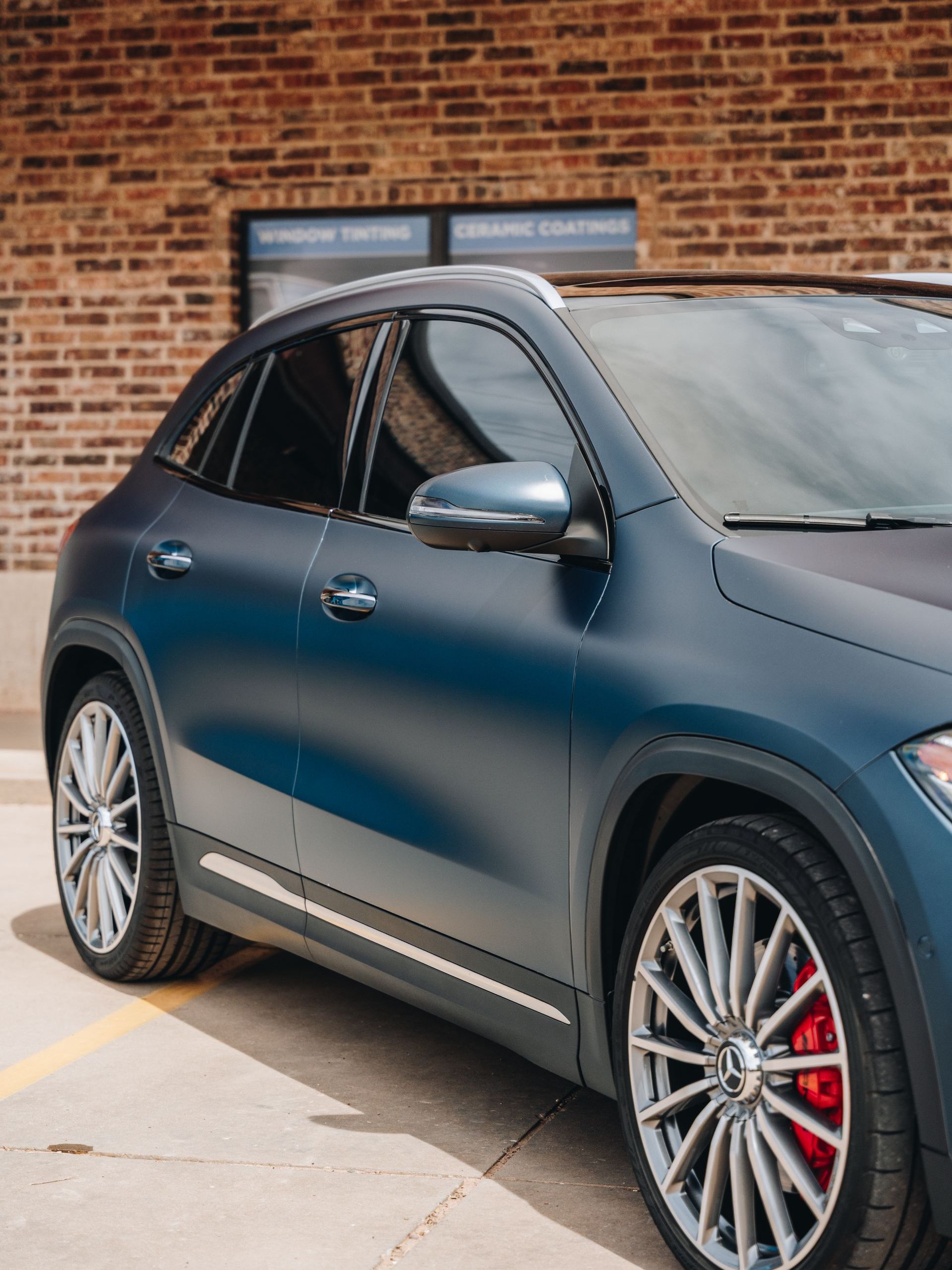 A blue car is parked in front of a brick building.