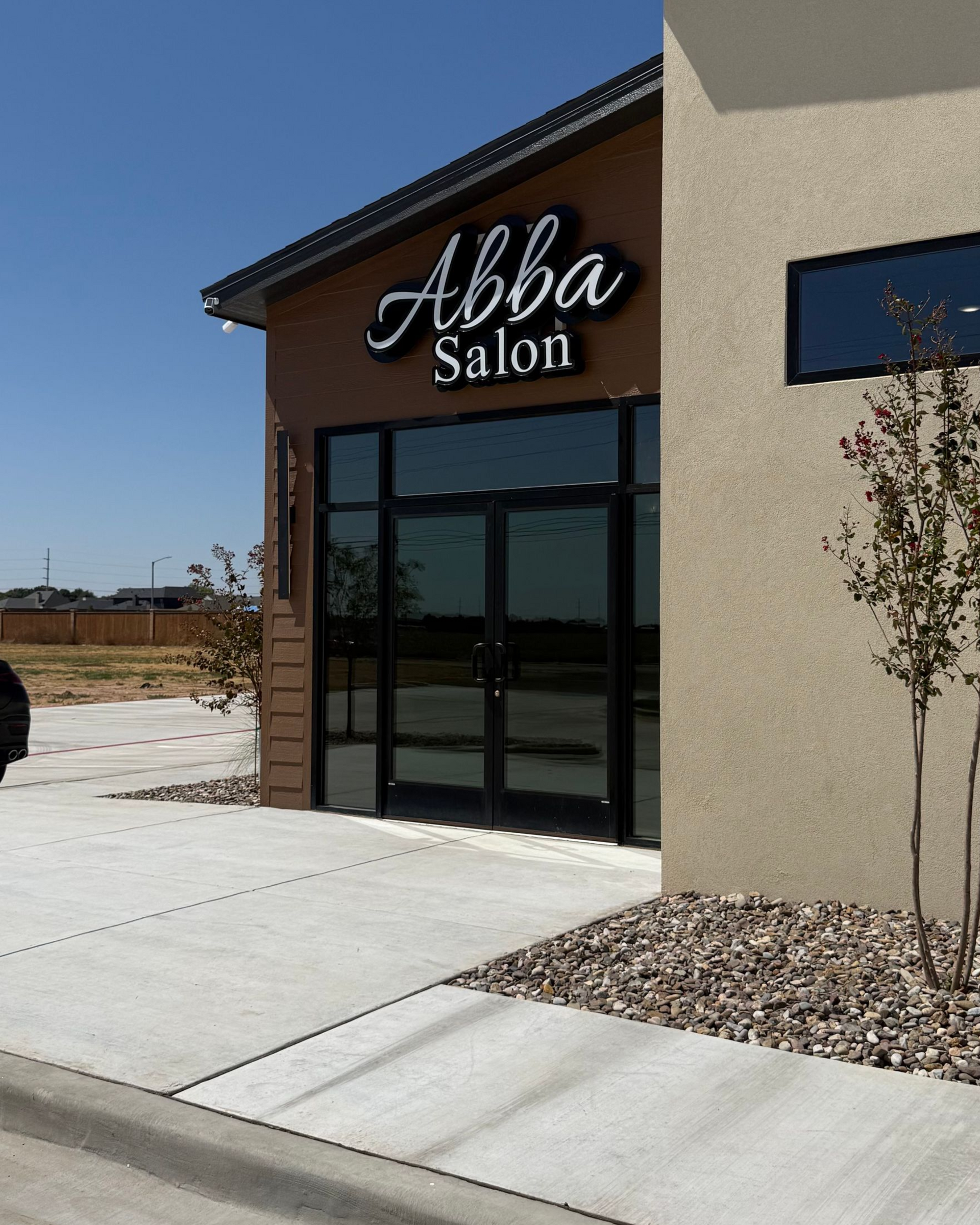 Abba Salon storefront with brown facade, glass entrance, and sidewalk in front