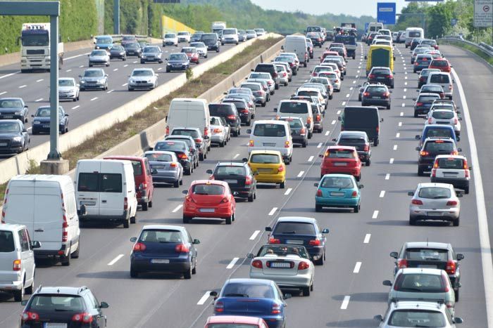 Heavy traffic on a multi-lane highway with many cars, vans, and trucks backed up in both directions