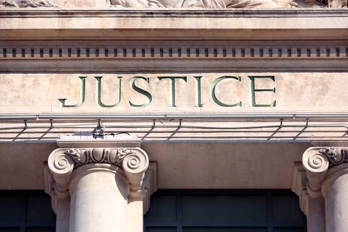 Stone courthouse facade with the word “JUSTICE” above ornate columns
