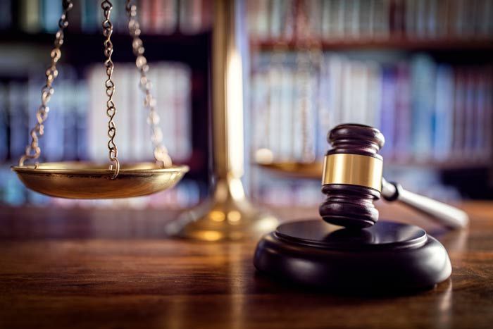 Law books and a judge's gavel on a desk, with justice scales in the foreground