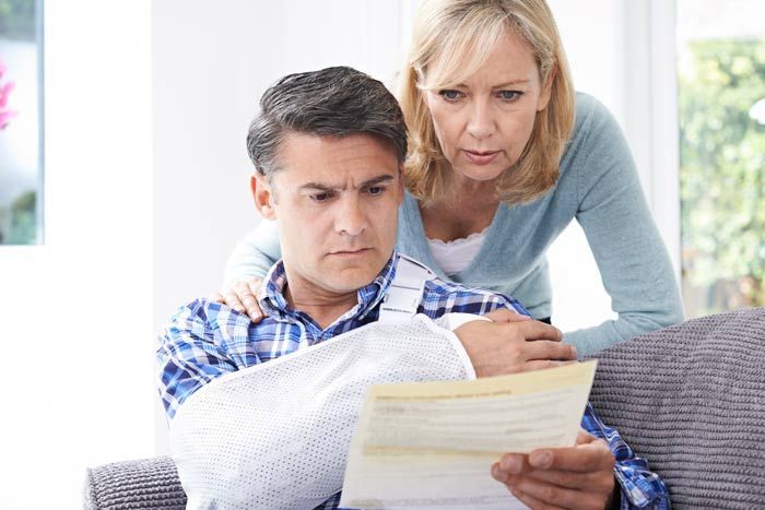 A worried couple reviews a letter together on a couch.
