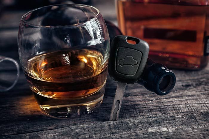 Whiskey glass beside a black car key fob on a rustic wooden table