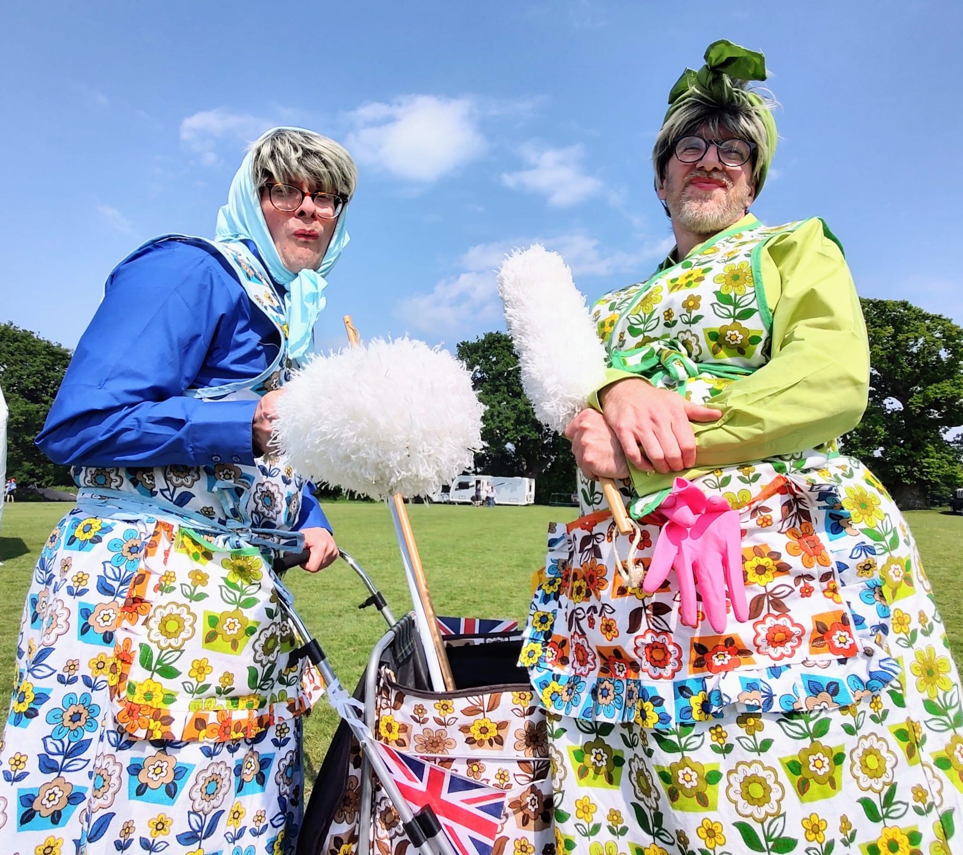 Two performers dress as 1950's housewives lean towards the camera with stoney faces