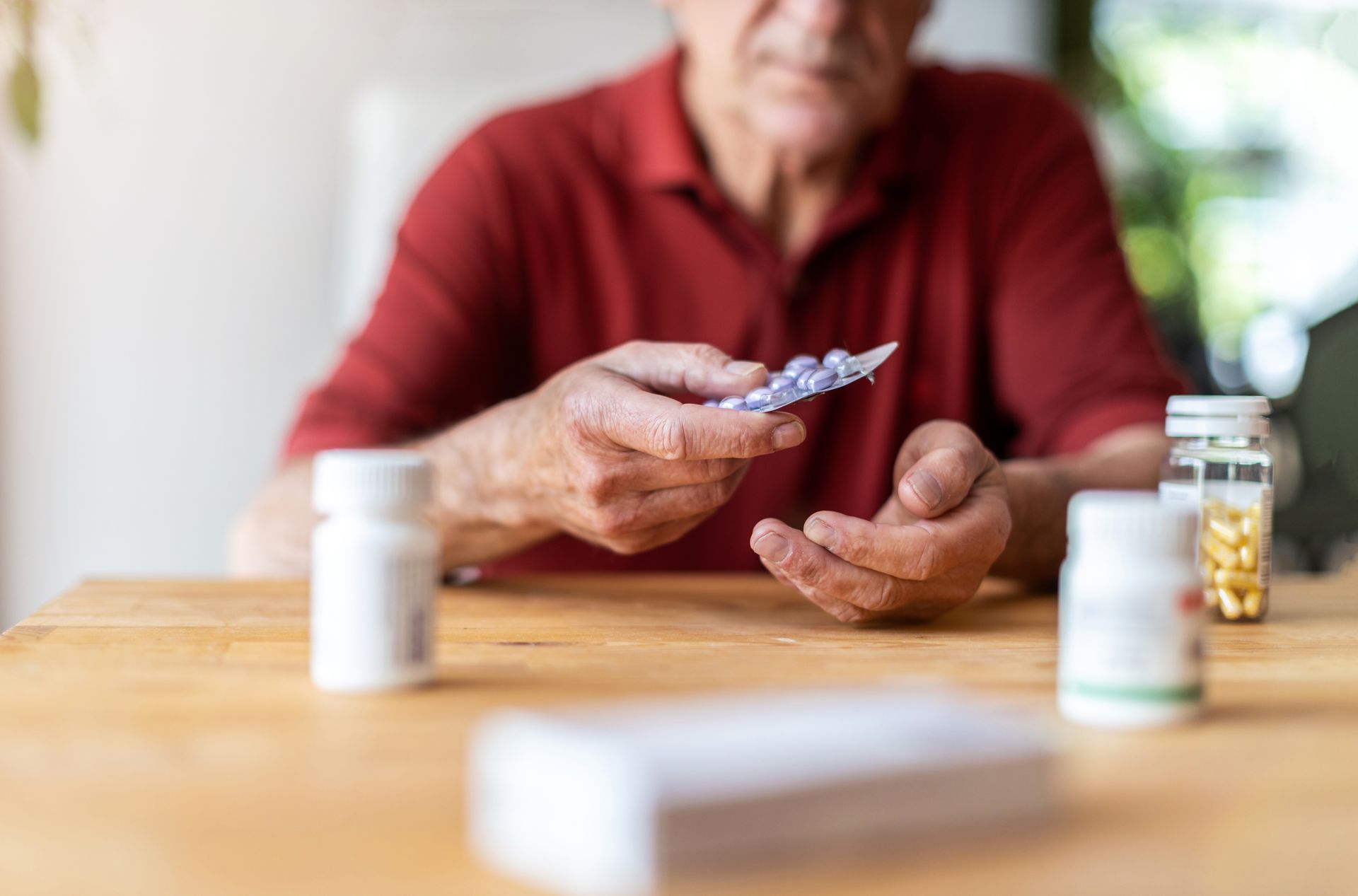 Person holding pills beside medicine bottles on a table