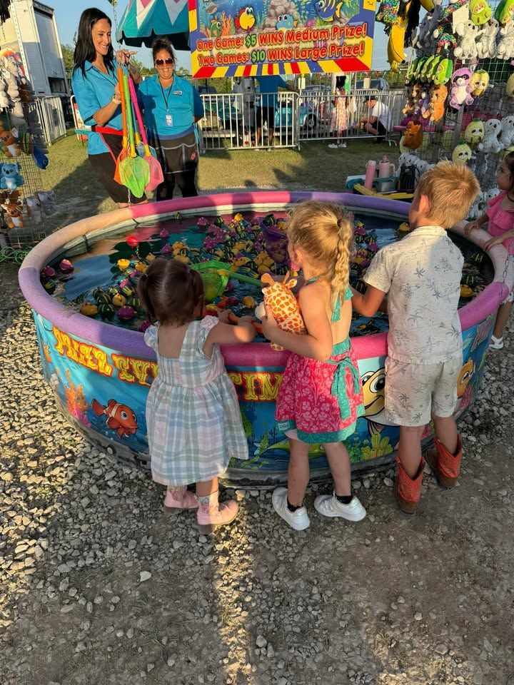 Children at a carnival tossing colorful balls into a bright flower-filled game basin