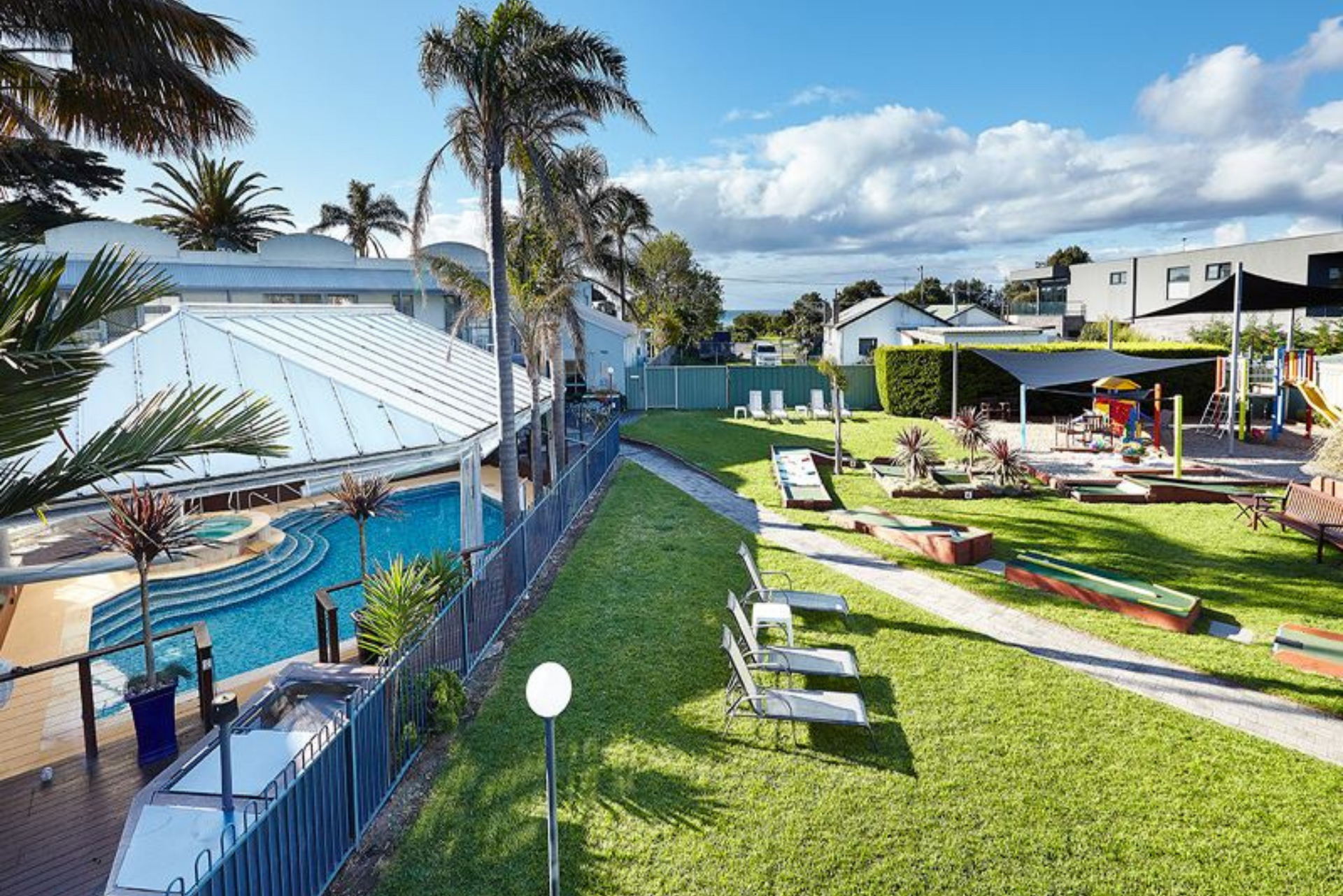 A large lawn with a swimming pool in the background