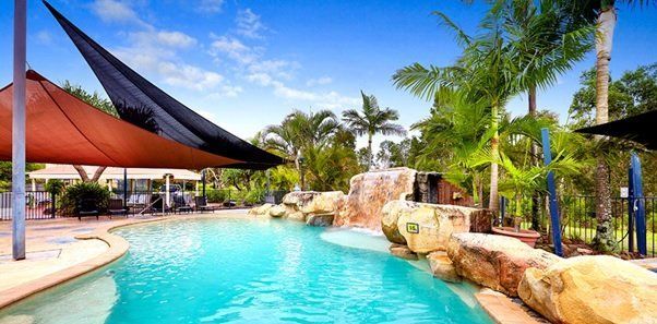 A large swimming pool surrounded by palm trees and a waterfall.
