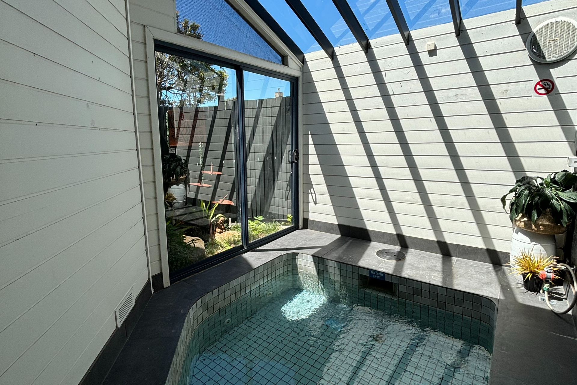 A small swimming pool in a room with a sliding glass door.