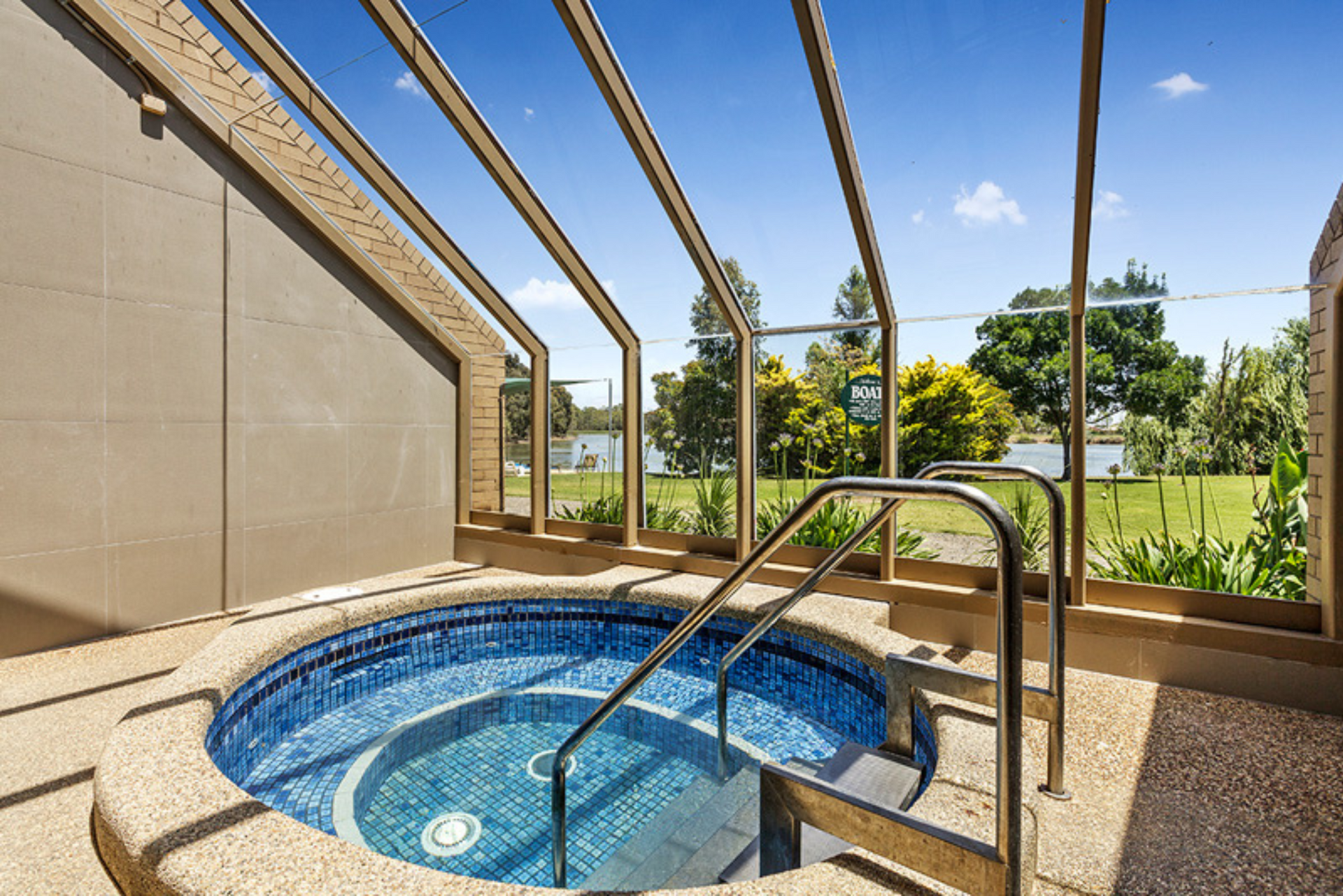 A hot tub with stairs leading to it is surrounded by a glass roof.