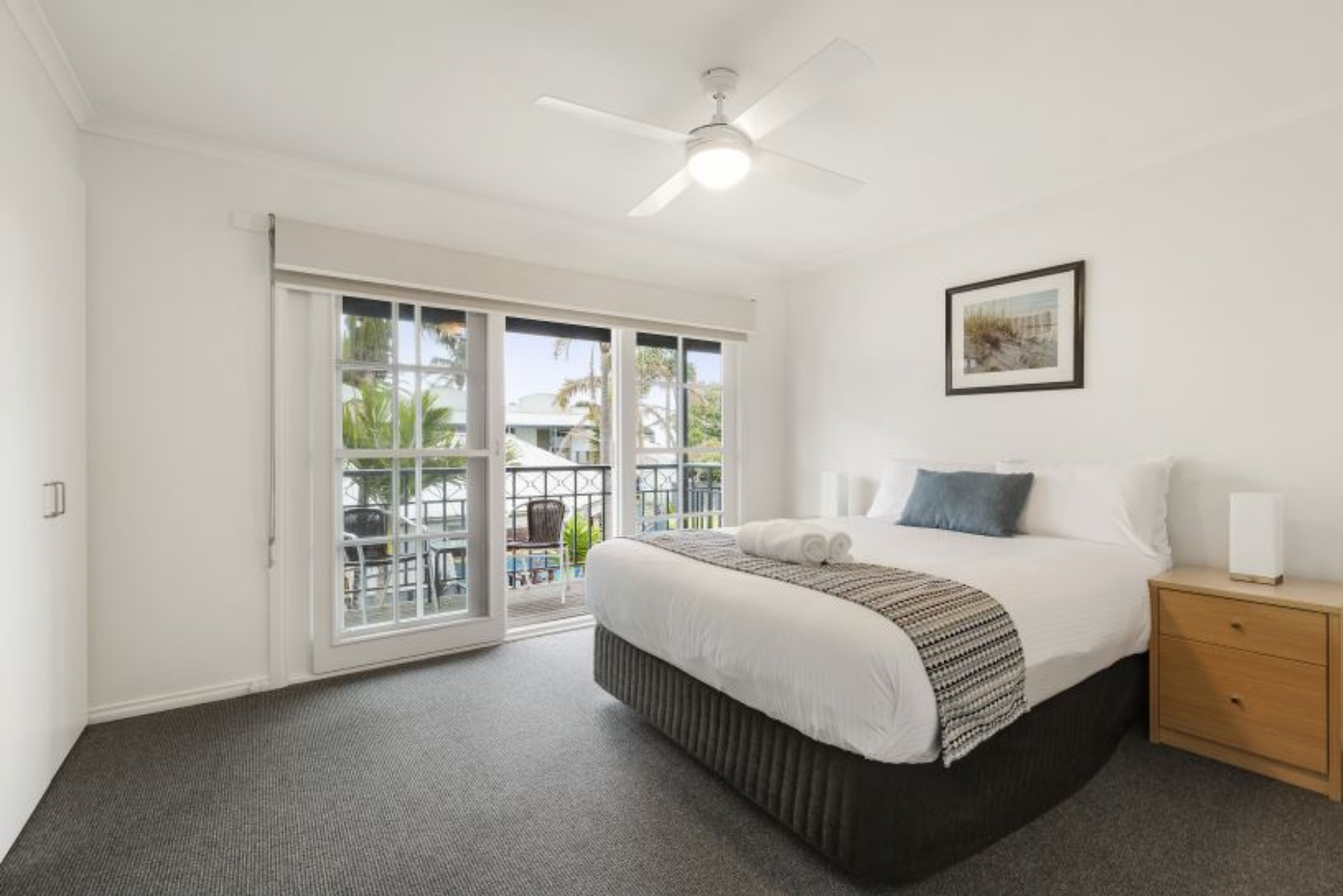 A bedroom with a king size bed and a ceiling fan.