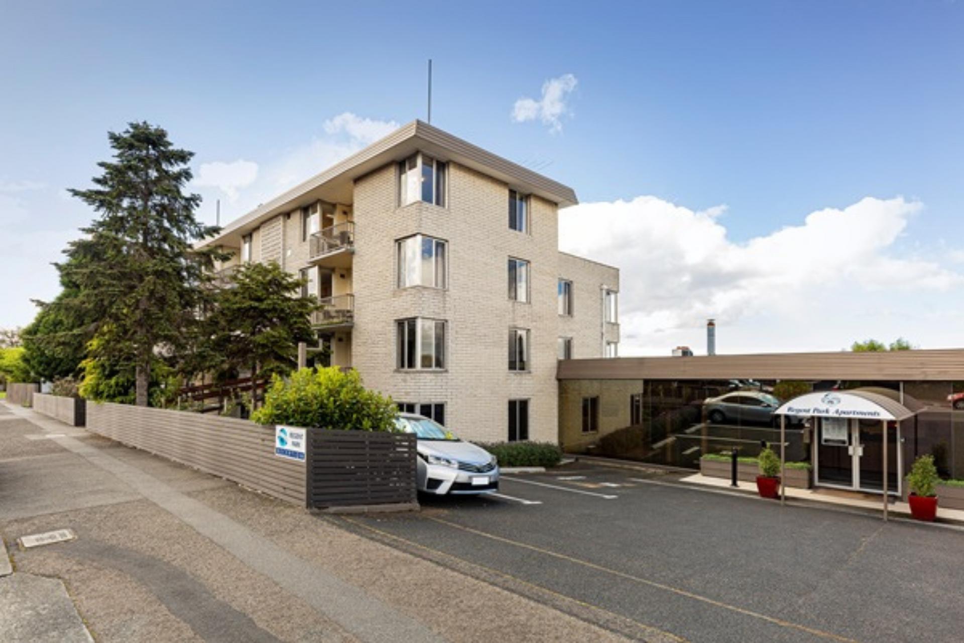 A car is parked in front of a large building.