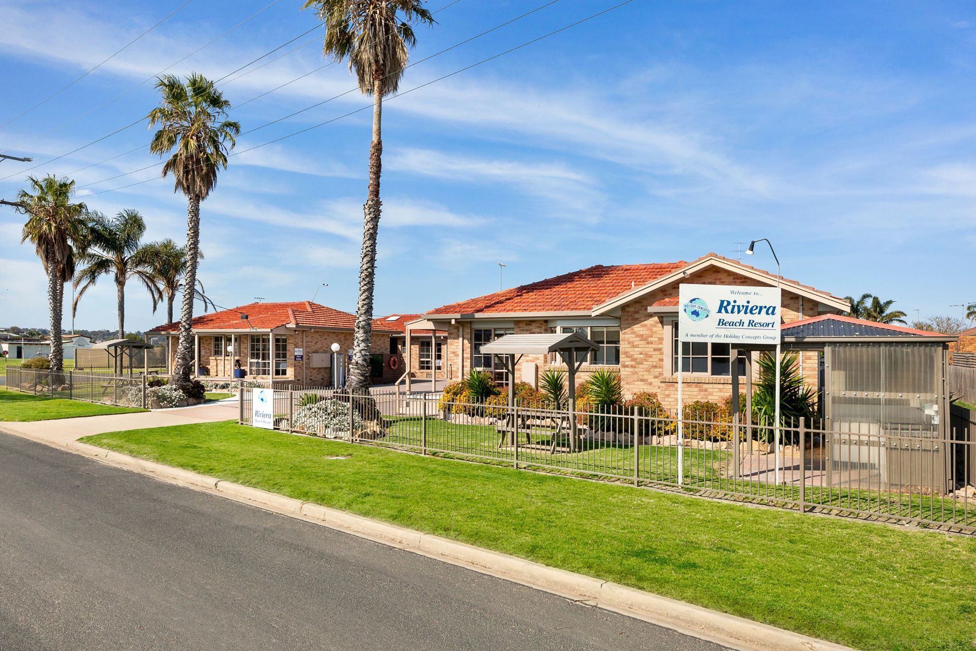 A row of houses with palm trees and a sign in front of them.