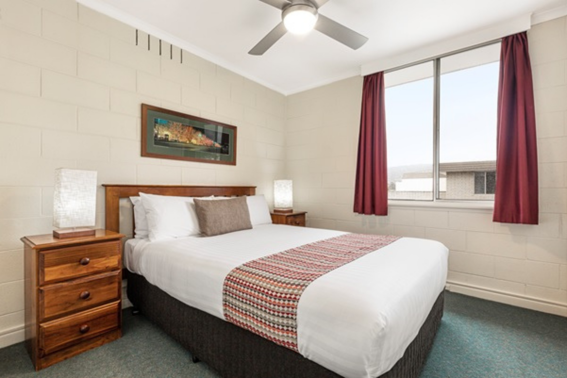 A hotel room with a king size bed and a ceiling fan.