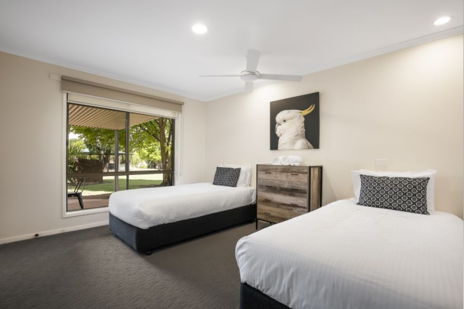 A bedroom with two beds , a dresser and a ceiling fan.