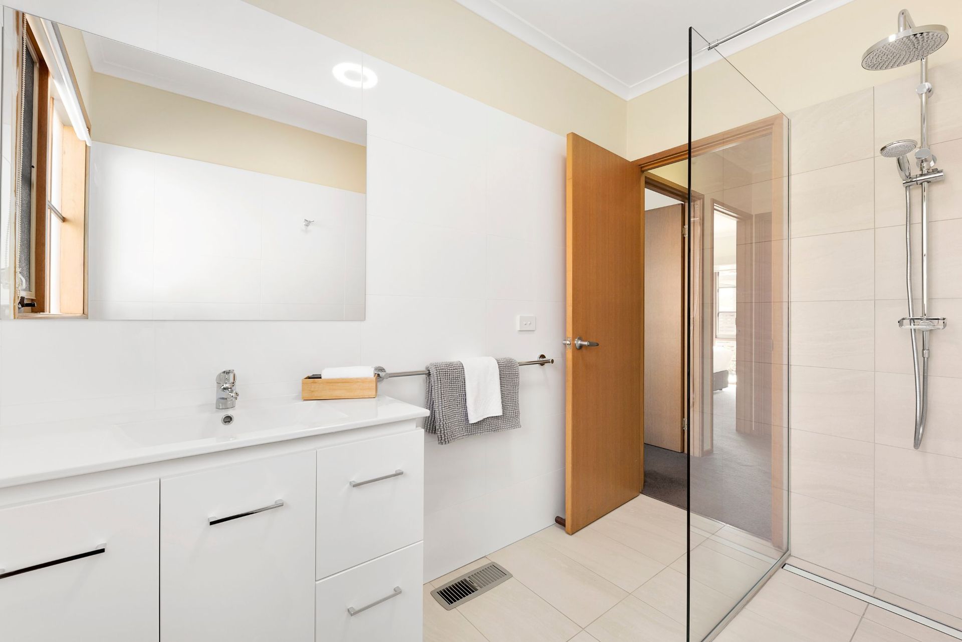 A bathroom with a sink , mirror and walk in shower.
