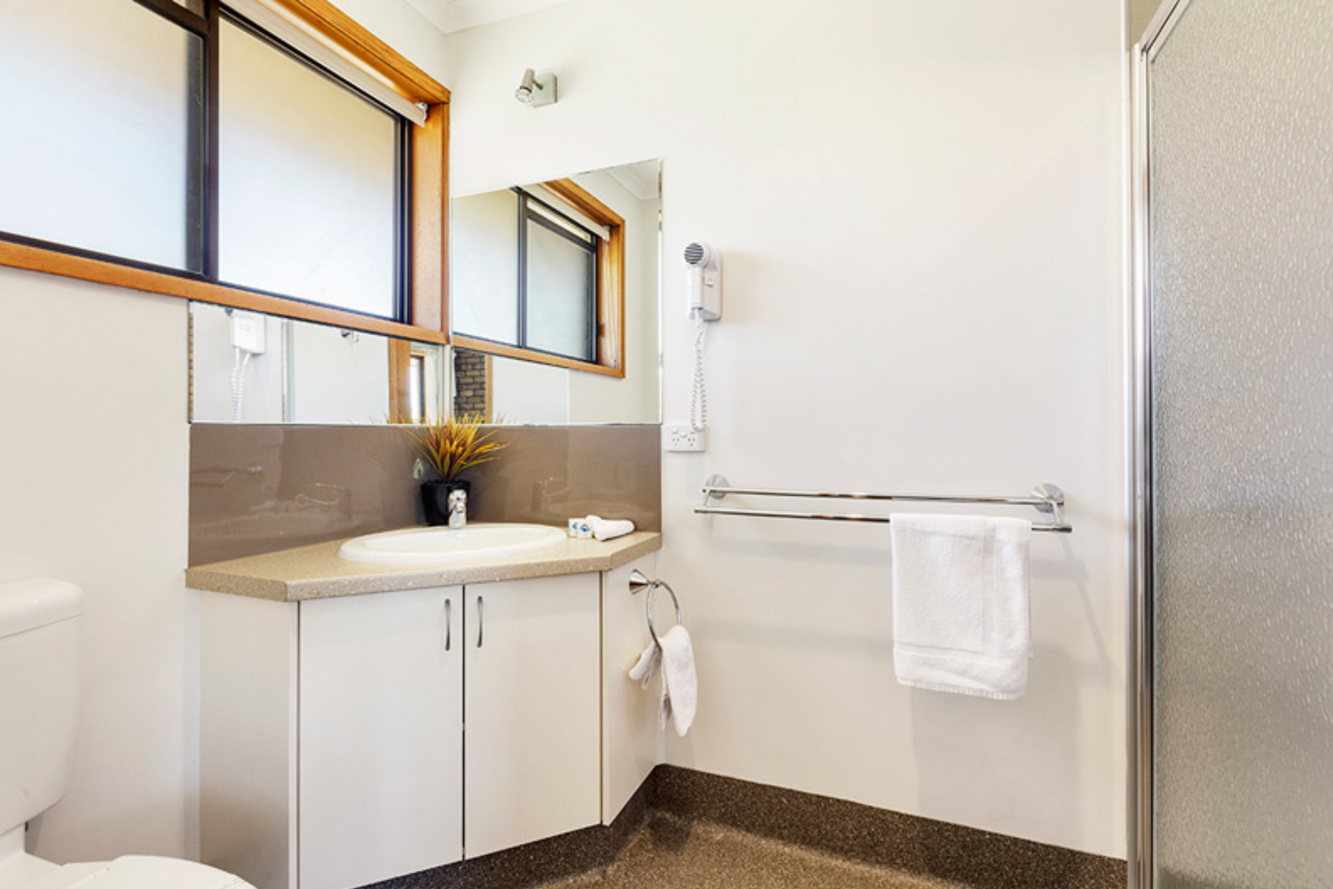A bathroom with a toilet , sink , mirror and shower.