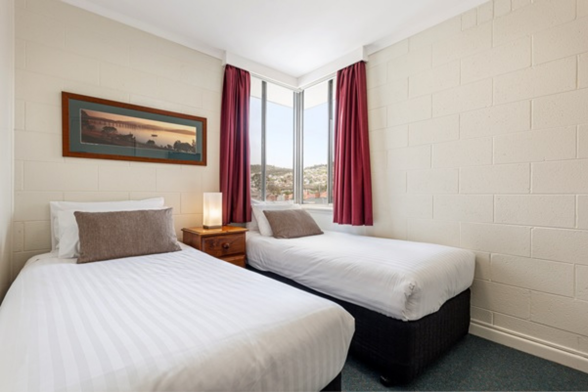 A hotel room with two beds and a window.