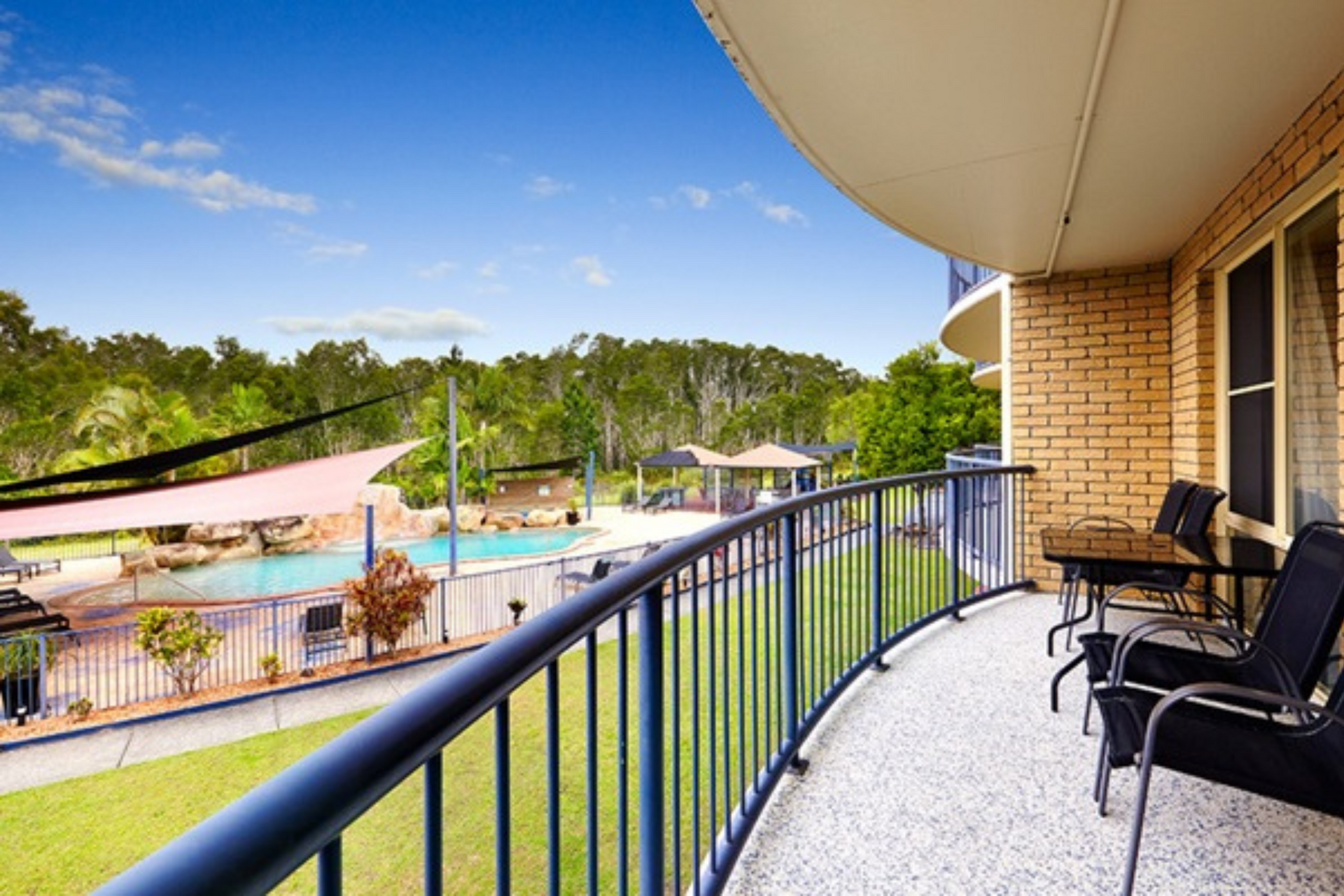 A balcony with a table and chairs overlooking a pool