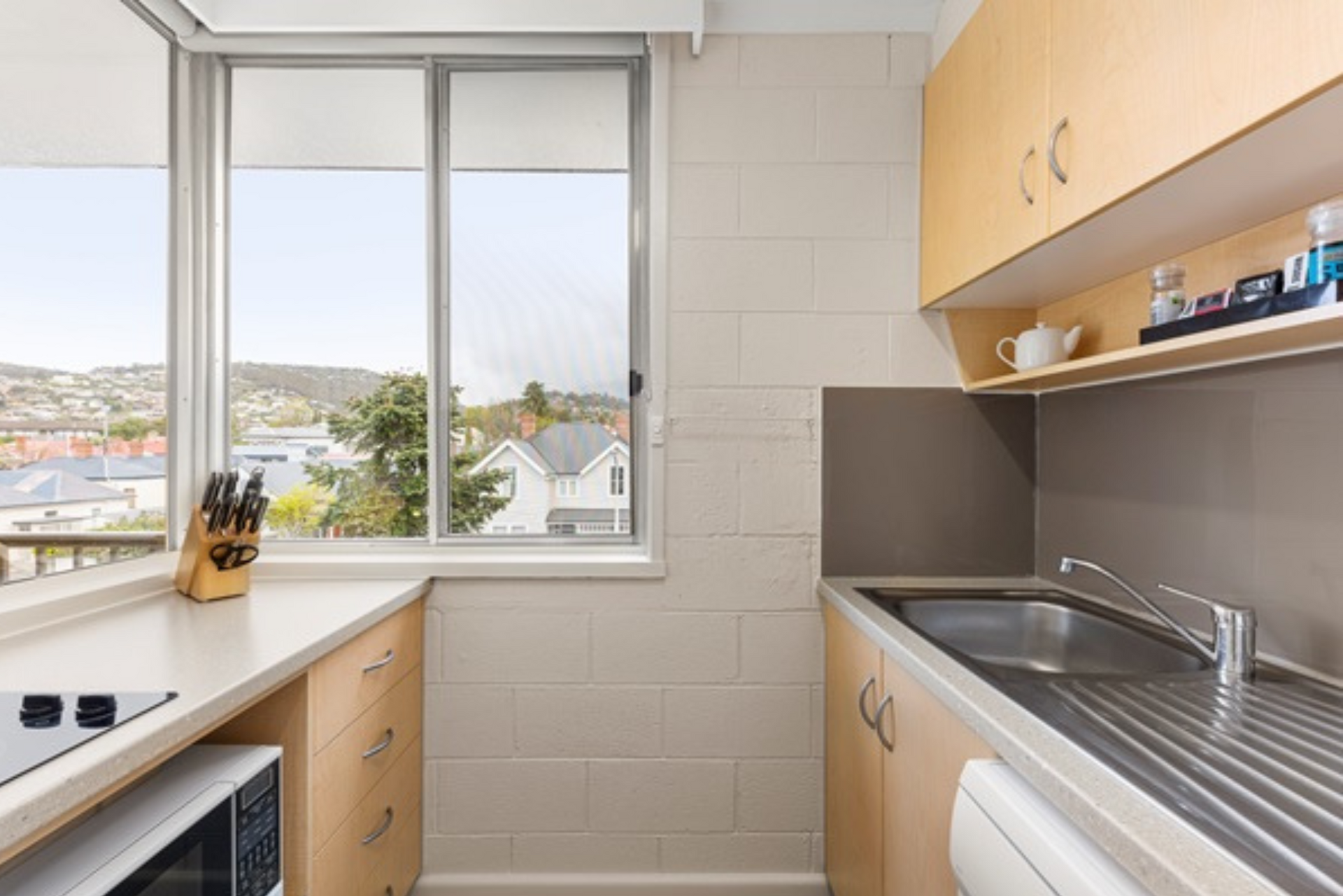 A kitchen with a sink , microwave , and window.