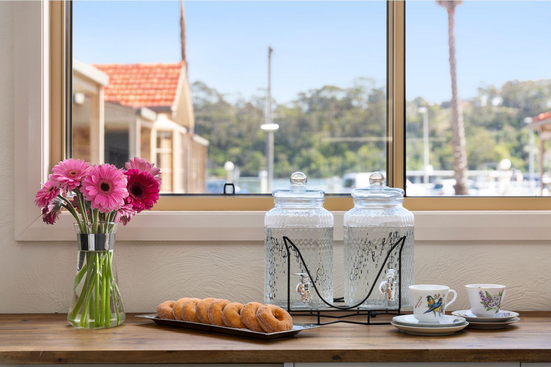 A vase of flowers sits on a counter next to a window.