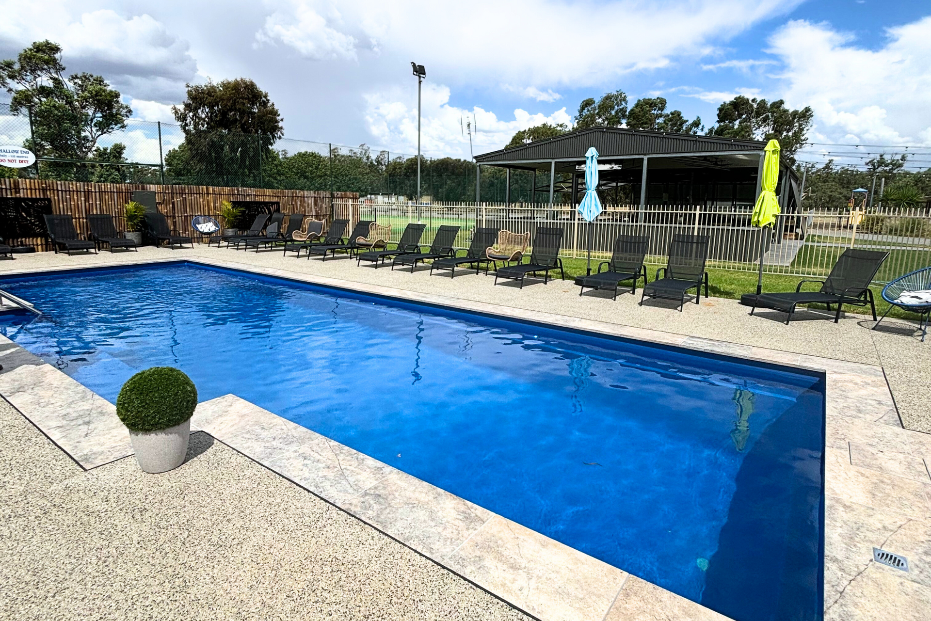 A large swimming pool surrounded by chairs and umbrellas