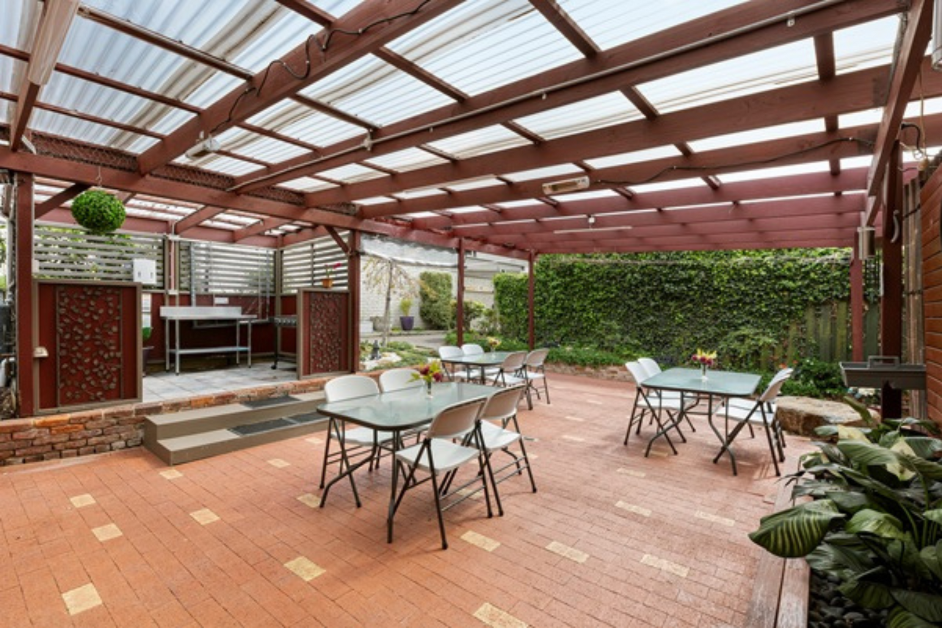 A patio with tables and chairs under a clear roof.