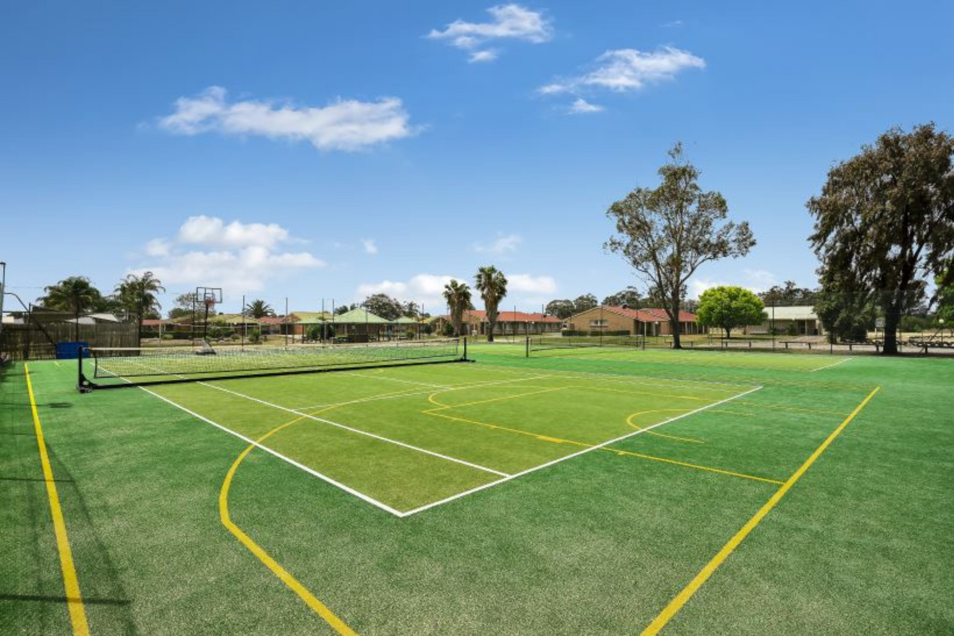 A tennis court with trees in the background and a blue sky