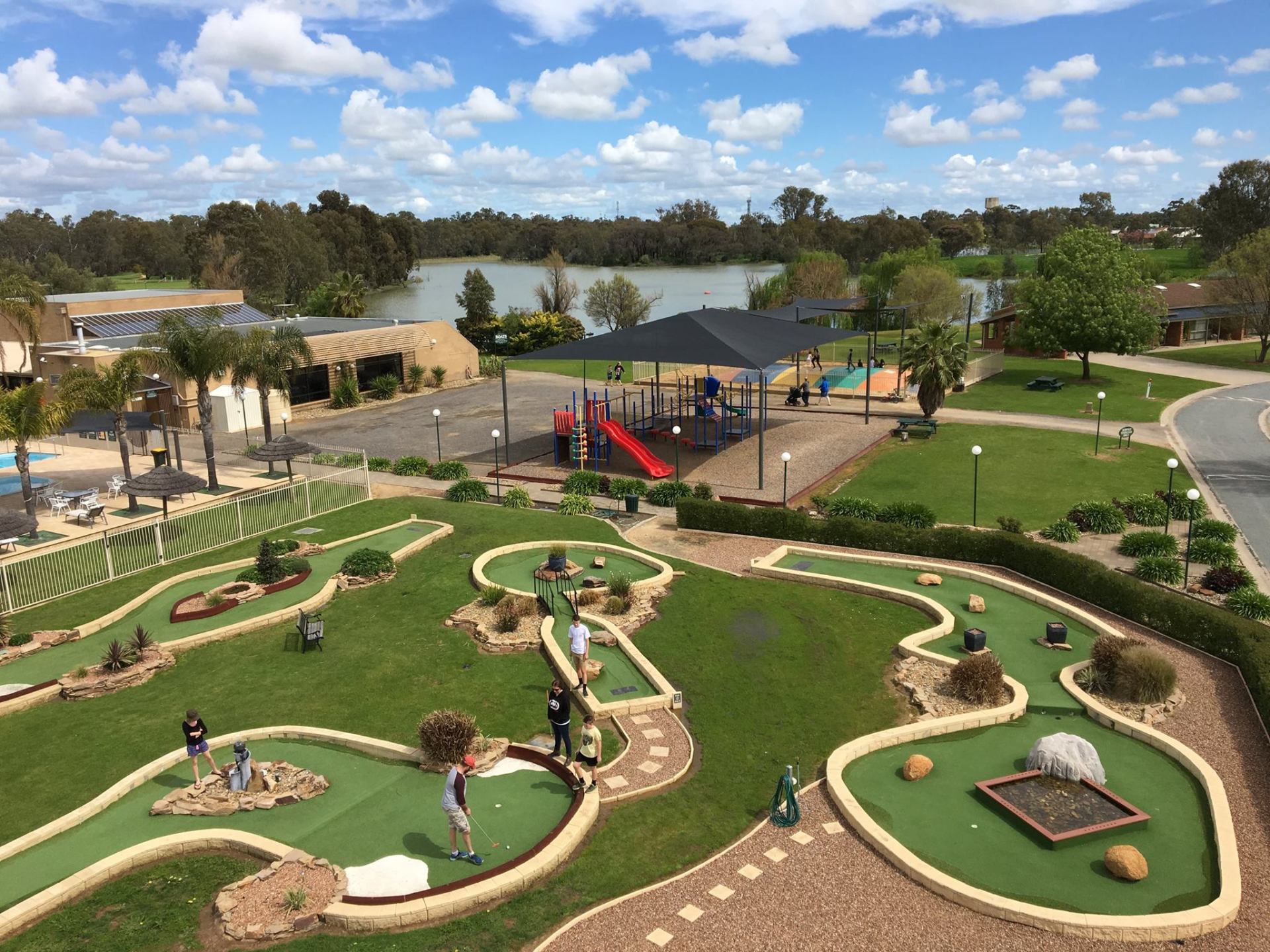 A group of people are playing mini golf in a park.