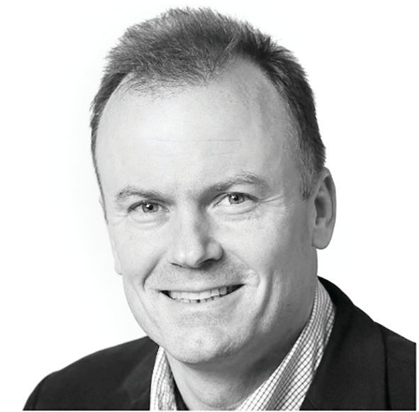Headshot of a smiling person in a dark blazer and collared shirt against a plain white background.