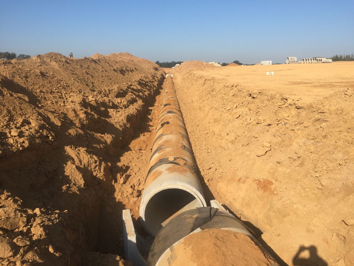 A large pipe is being installed in the dirt.