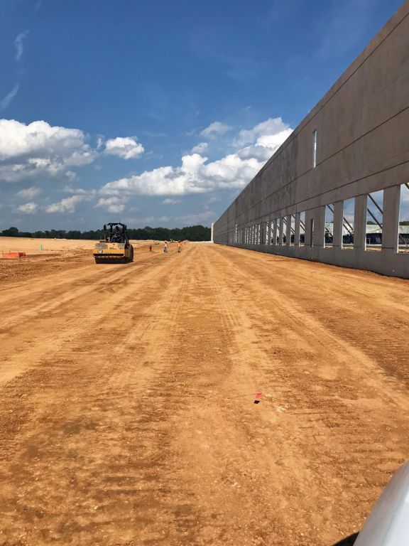 A large building is being built on a dirt road