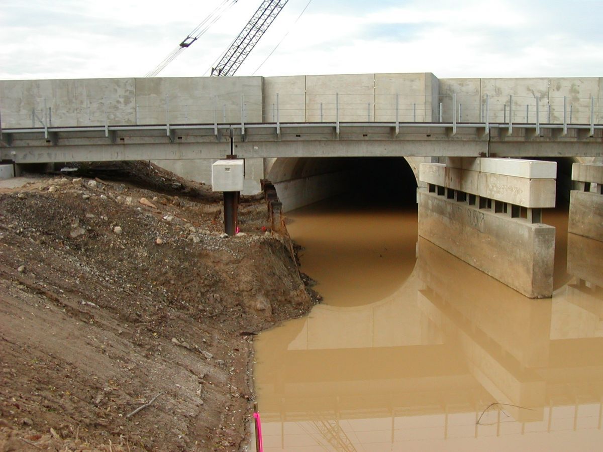 A bridge over a body of water with a crane in the background
