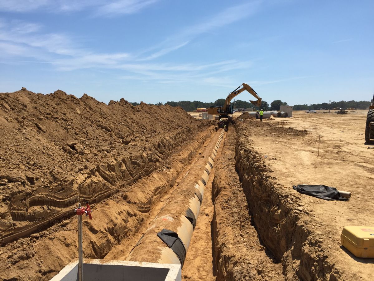 A large excavator is digging a trench in a dirt field.