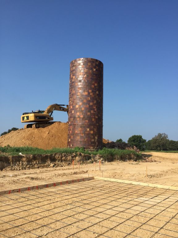 A large brick silo is being built with a bulldozer in the background