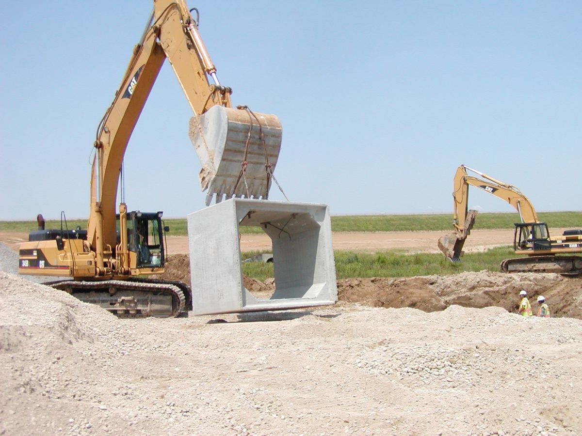A yellow excavator is digging a hole in the dirt