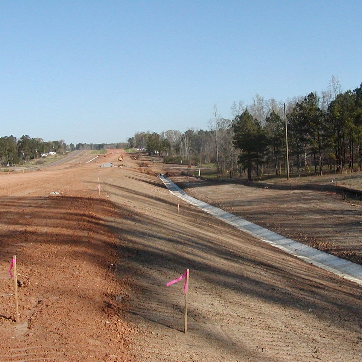 A dirt road with pink markers on the side of it