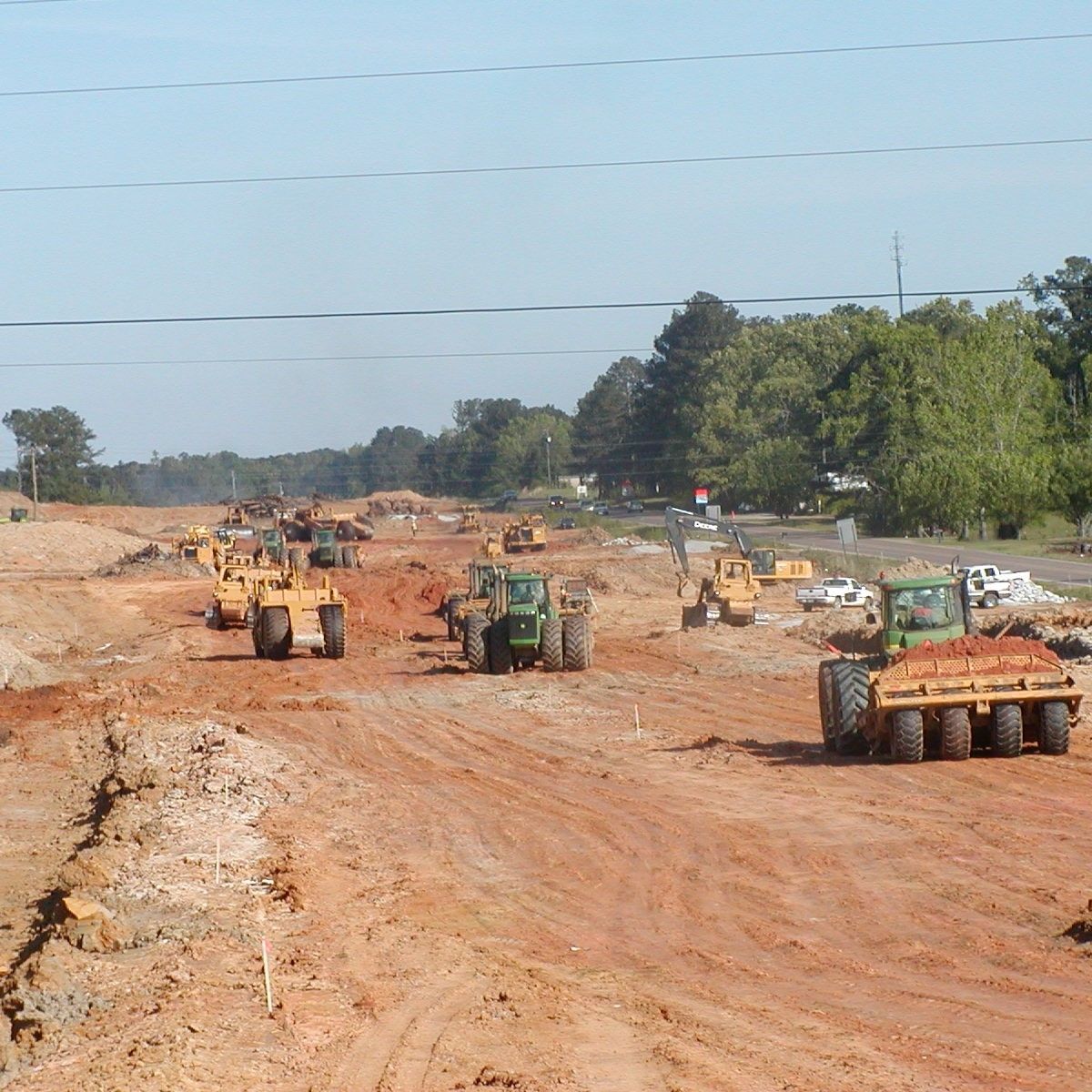A row of construction vehicles on a dirt road