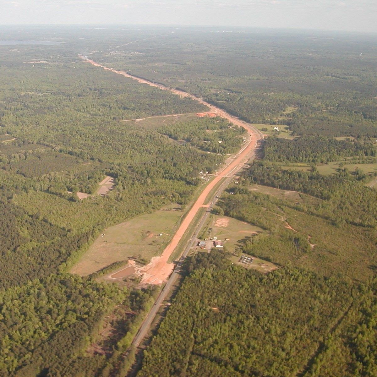 An aerial view of a dirt road surrounded by trees