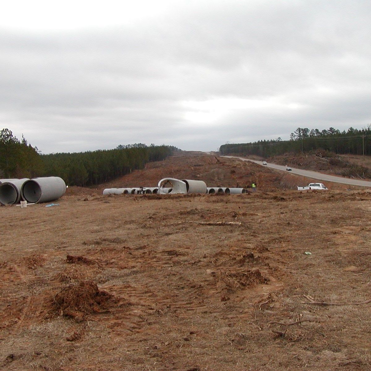 A dirt field with a highway in the background