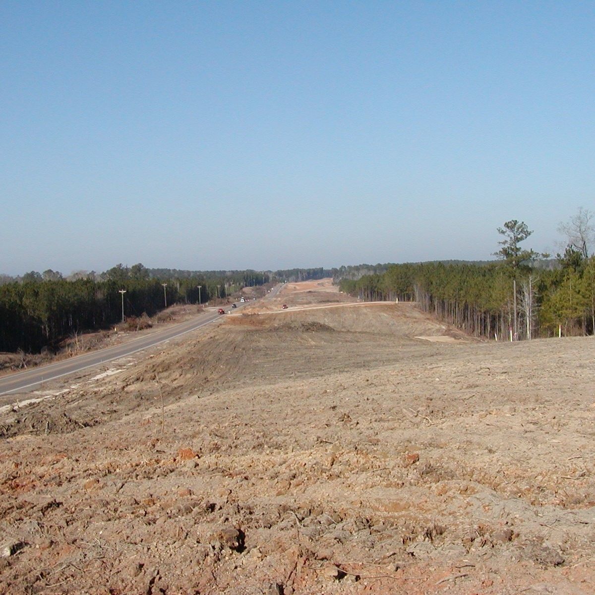 A dirt road going through a field with trees in the background
