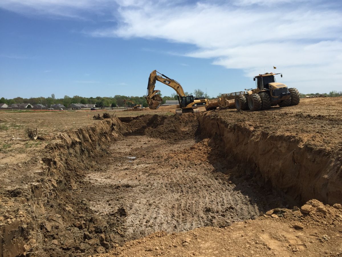 A bulldozer is digging a hole in the dirt in a field.