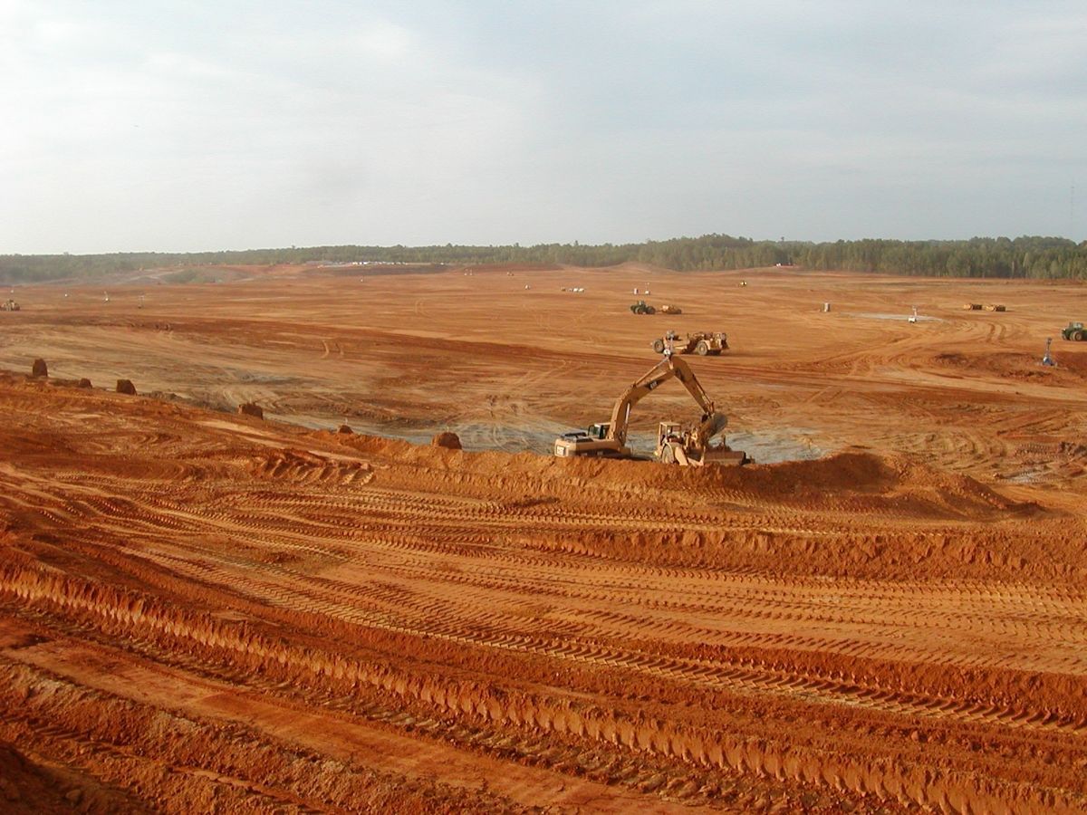 A large dirt field with a bulldozer in the middle of it.