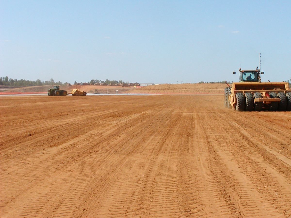 A group of tractors are working on a dirt road.