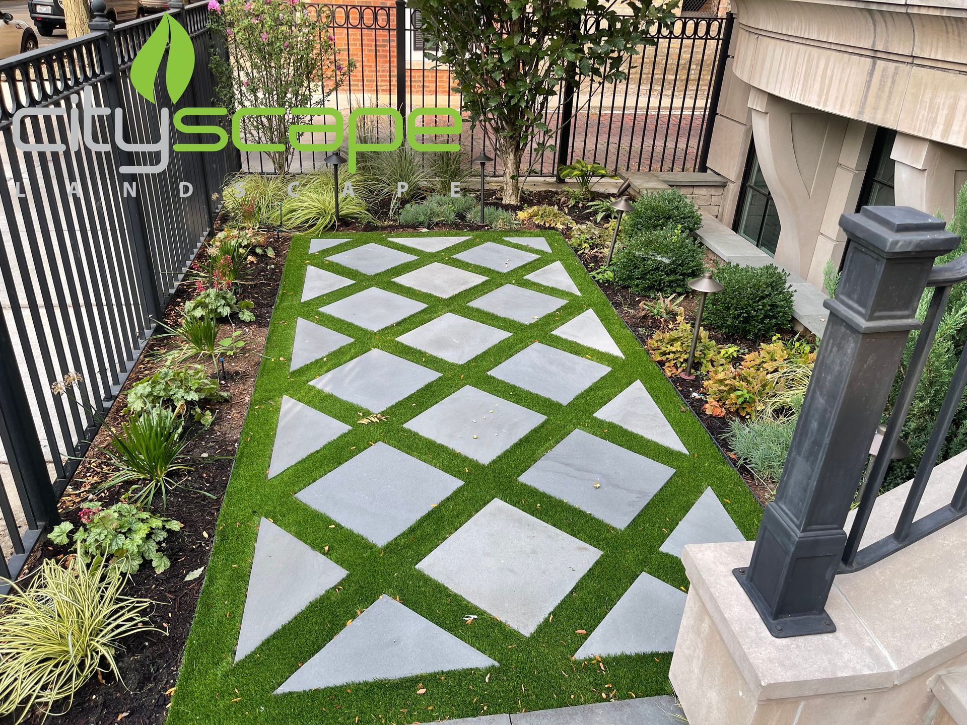 Landscaped pathway with square pavers in a diamond pattern surrounded by greenery.